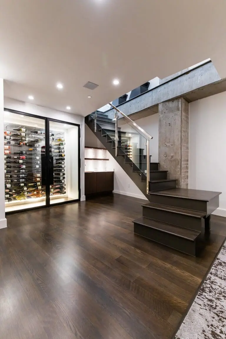 Renowned Group modern home wine cellar under stairs with glass display and dark wood floors