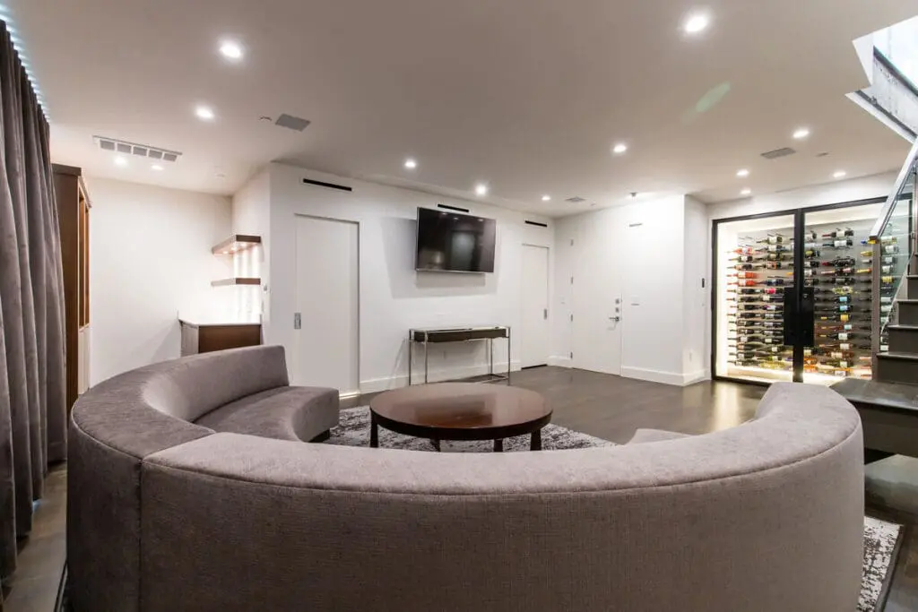 Renowned Group modern media room with curved sofa and glass wine display