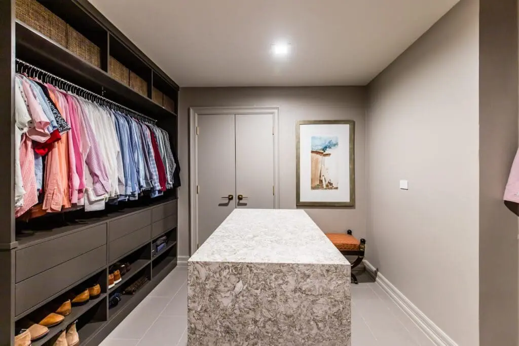 Renowned Group modern mens walk in closet with custom storage and marble island