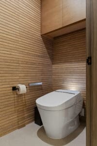 Modern toilet with wood-paneled walls by StyleCraft Cabinets in a Texas master bathroom.