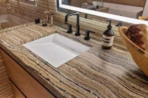 Master bathroom vanity featuring a natural stone top and no-hardware design by StyleCraft Cabinets, Dallas.