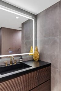 Modern bathroom vanity with golden accents and no visible hardware in Dallas, TX by StyleCraft Cabinets.
