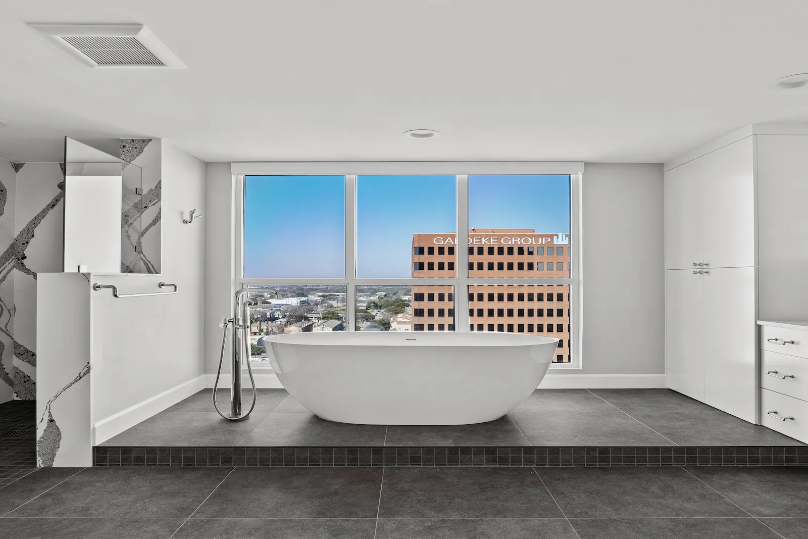 Bathroom remodel in Dallas by Renowned Group freestanding soaking tub on raised platform with skyline views