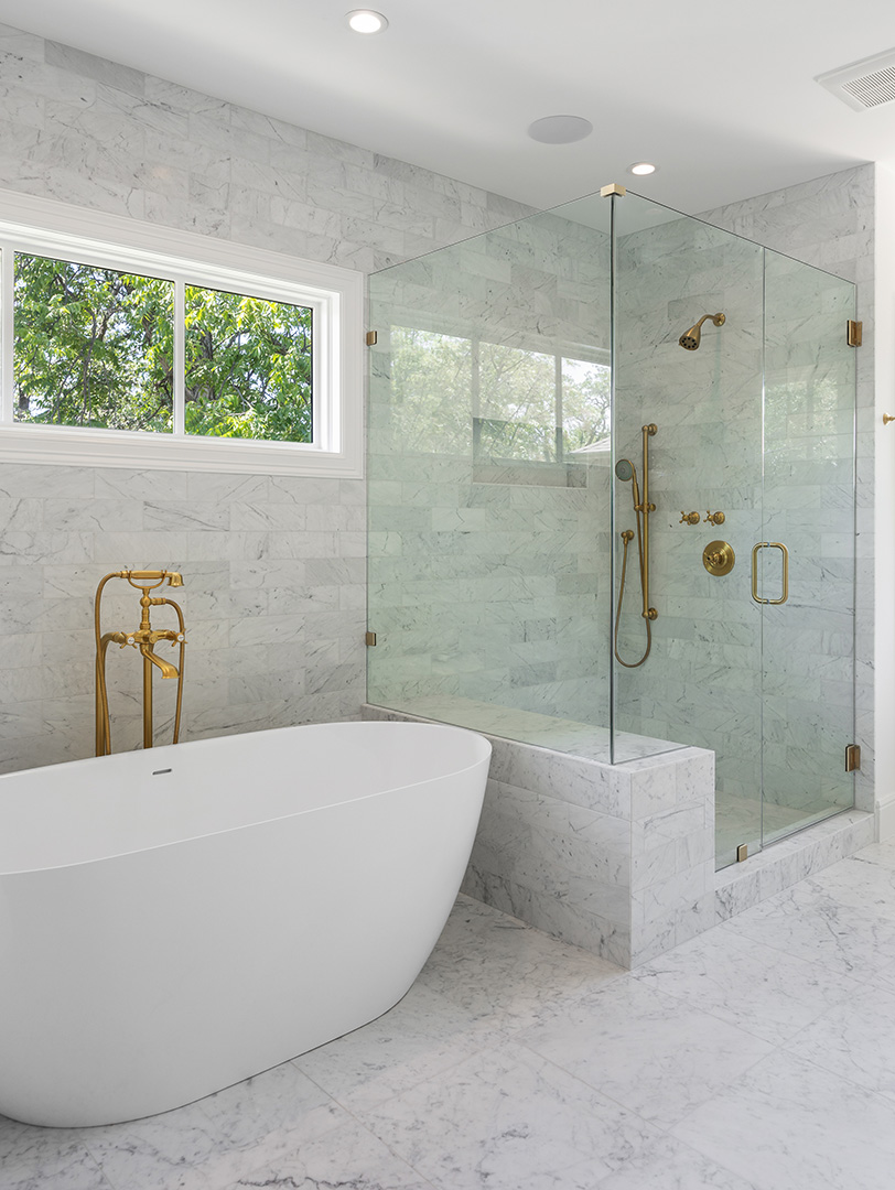 Bathroom remodel in Dallas by Renowned Group freestanding tub with gold fixtures and marble tile
