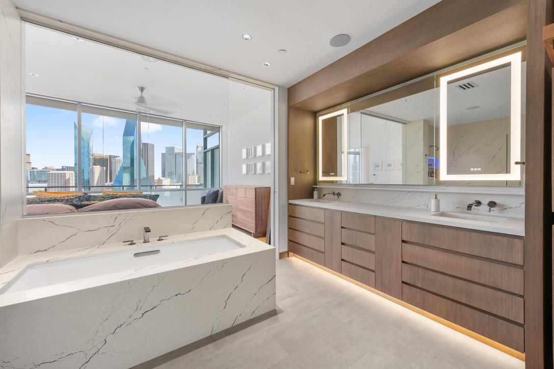 Bathroom remodel in Dallas by Renowned Group marble soaking tub with LED mirrors and Dallas skyline views