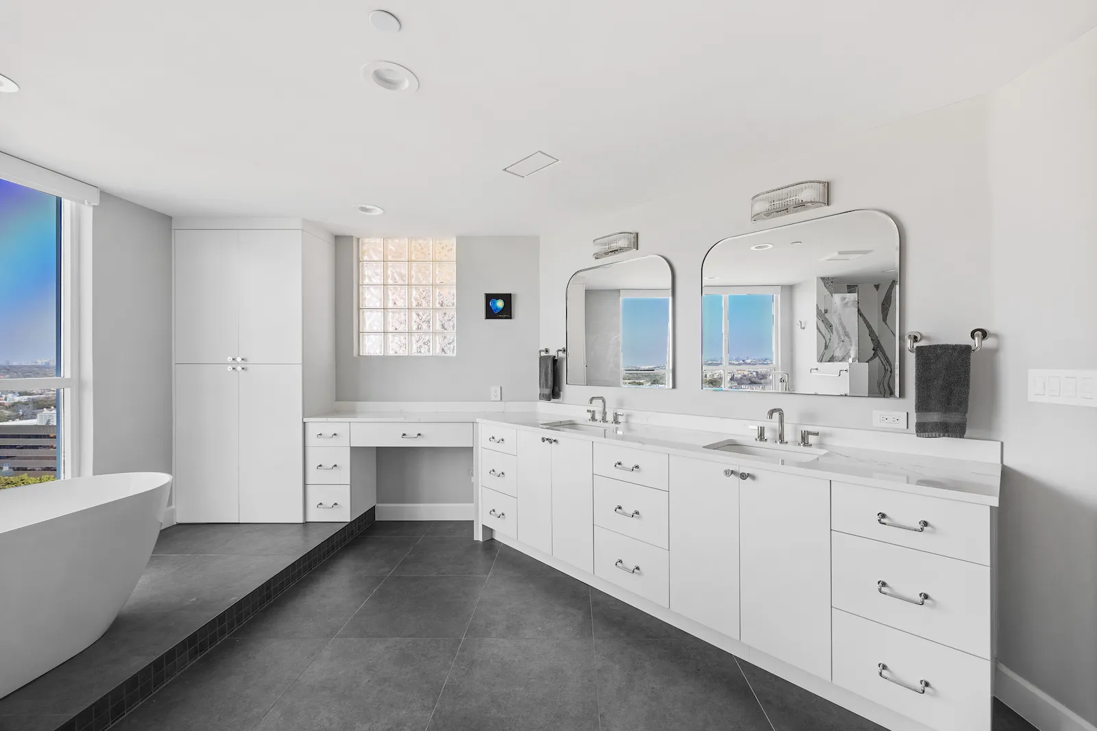 Bathroom remodel in Dallas by Renowned Group white double vanity with makeup station and city views