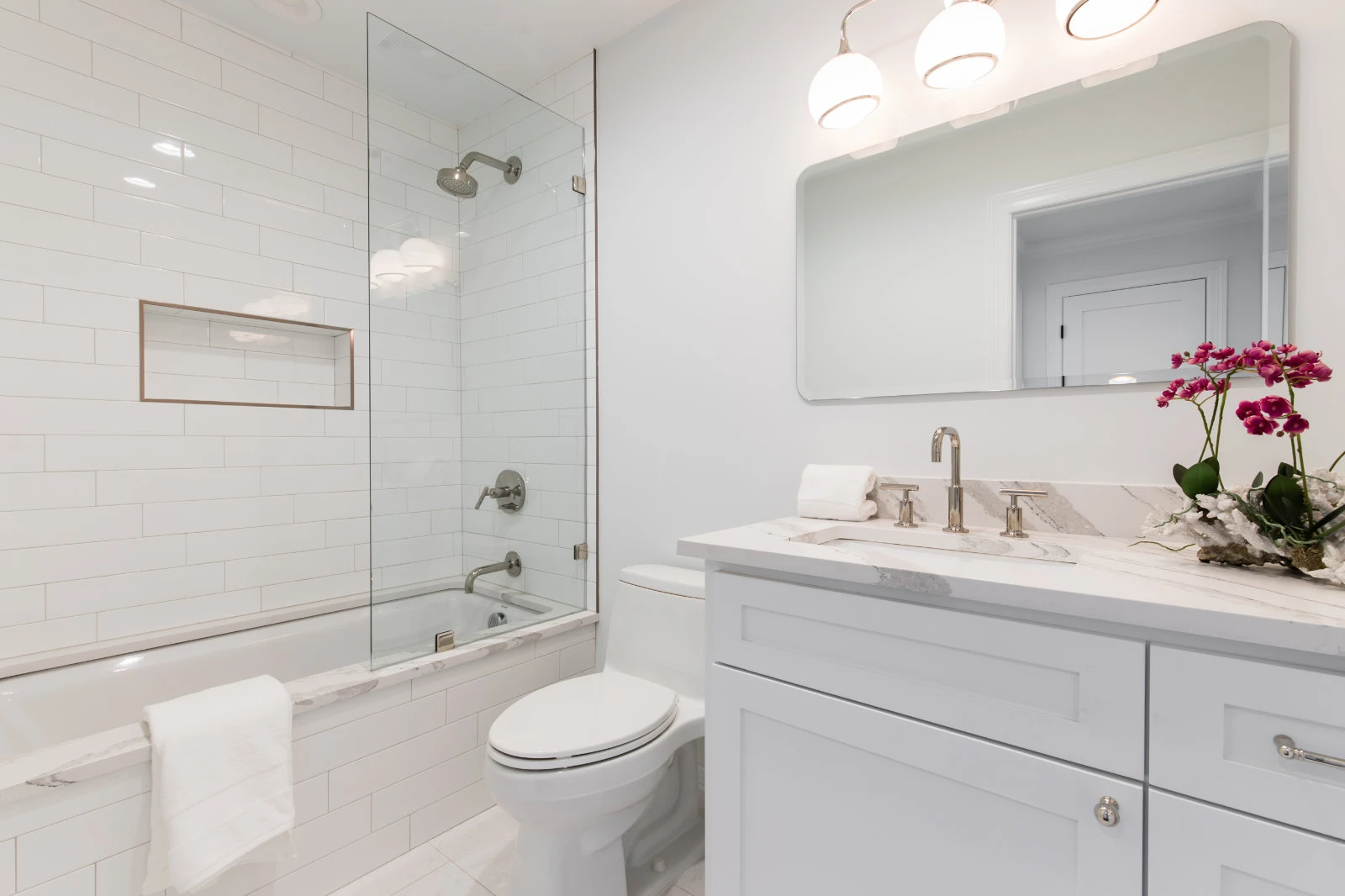Bathroom remodel in Dallas by Renowned Group white subway tile shower tub combo with marble vanity