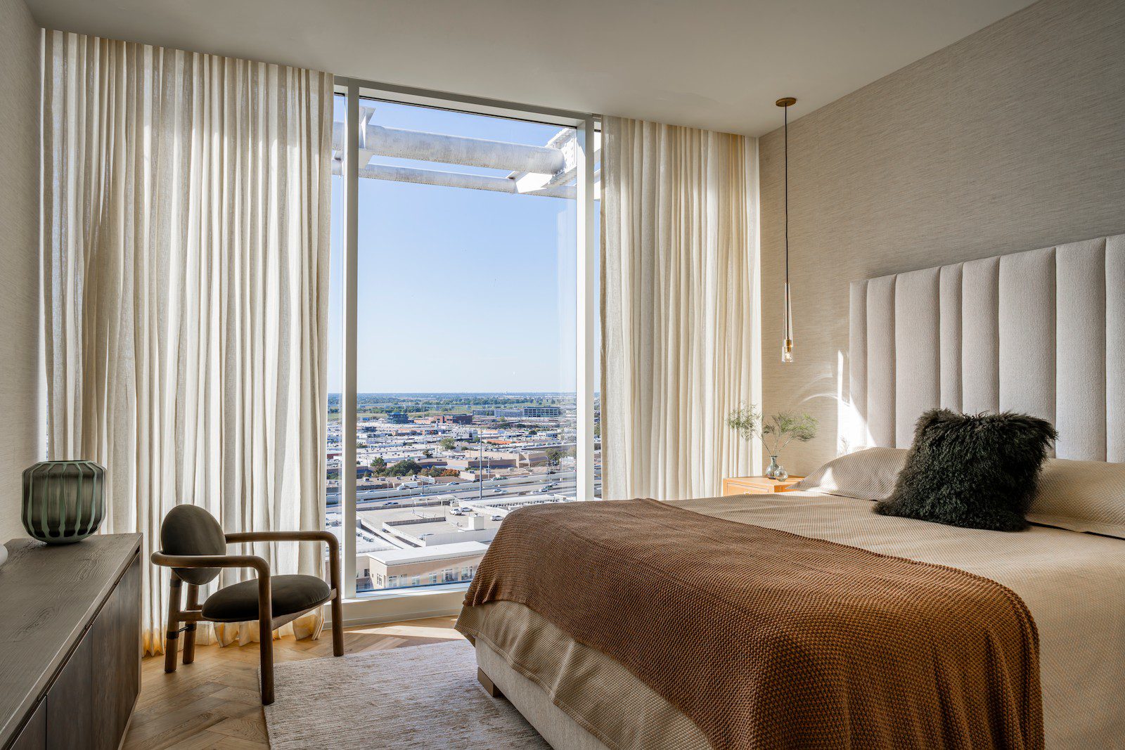 Condo Renovation in Dallas by Renowned Group primary bedroom with channel tufted headboard and city view