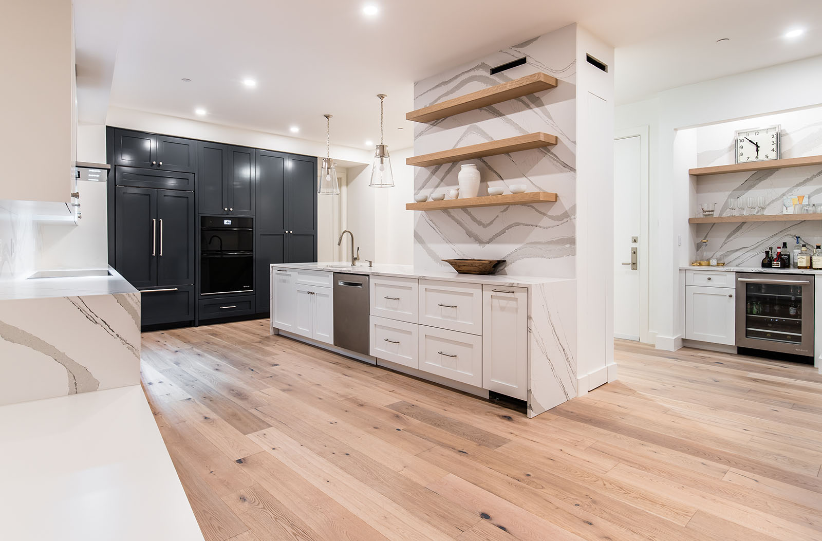 Kitchen remodel in Dallas by Renowned Group black and white cabinets with marble waterfall island and floating shelves