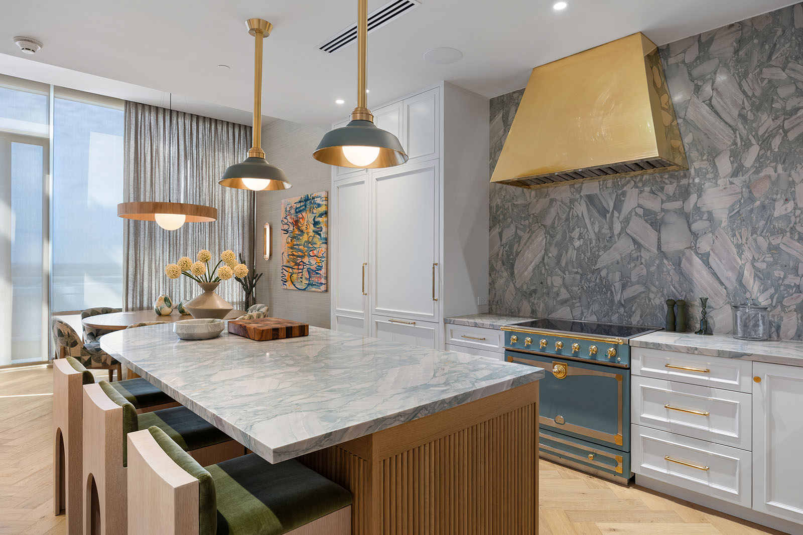 Kitchen remodel in Dallas by Renowned Group white kitchen with brass hood and marble island