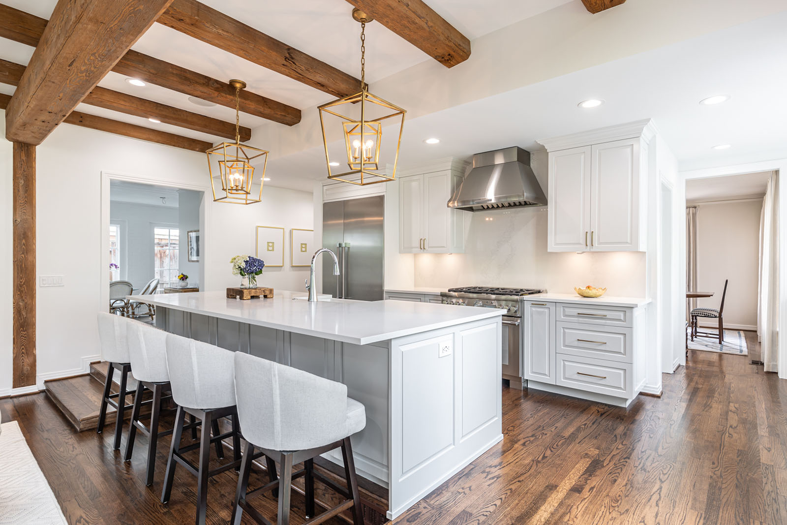 Kitchen remodel in Dallas by Renowned Group white kitchen with reclaimed wood beams and gold lantern pendants