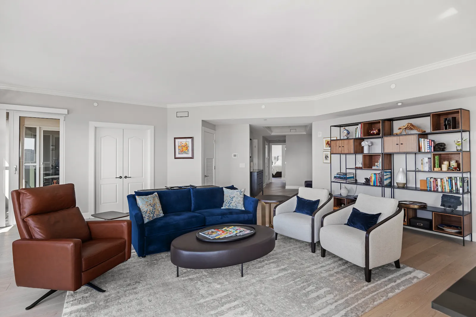 Turtle Creek Condo Remodel by Renowned Group showing a modern living room with blue sofa leather recliner and open bookshelf