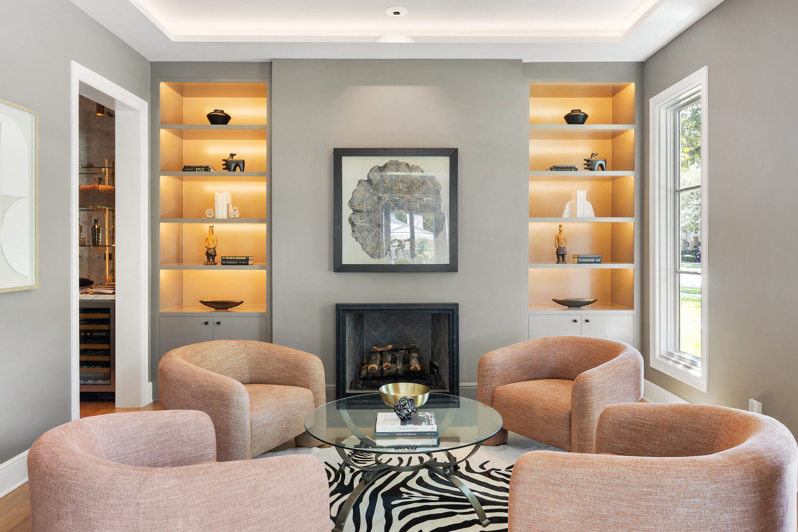Whole Home Remodel in Dallas by Renowned Group sitting room with lit built in shelving and black tile fireplace